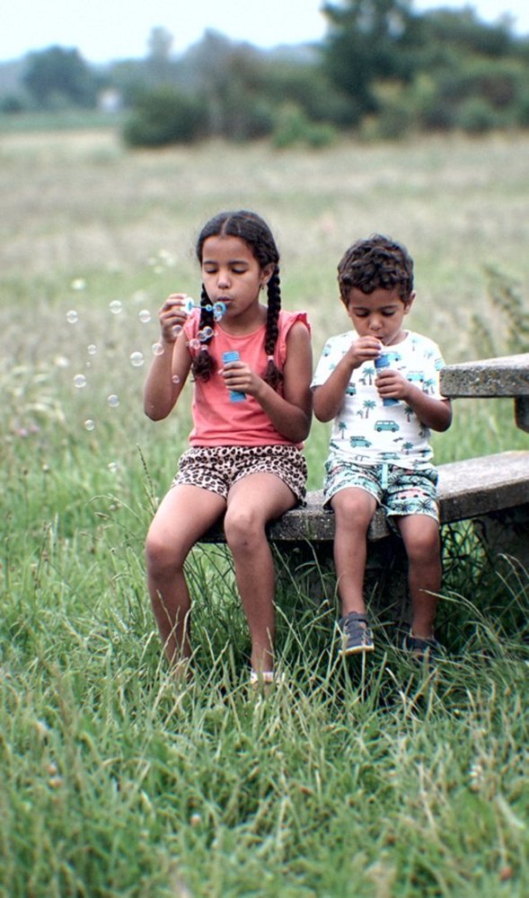 Foto van twee kinderen die bellen blazen op een bankje