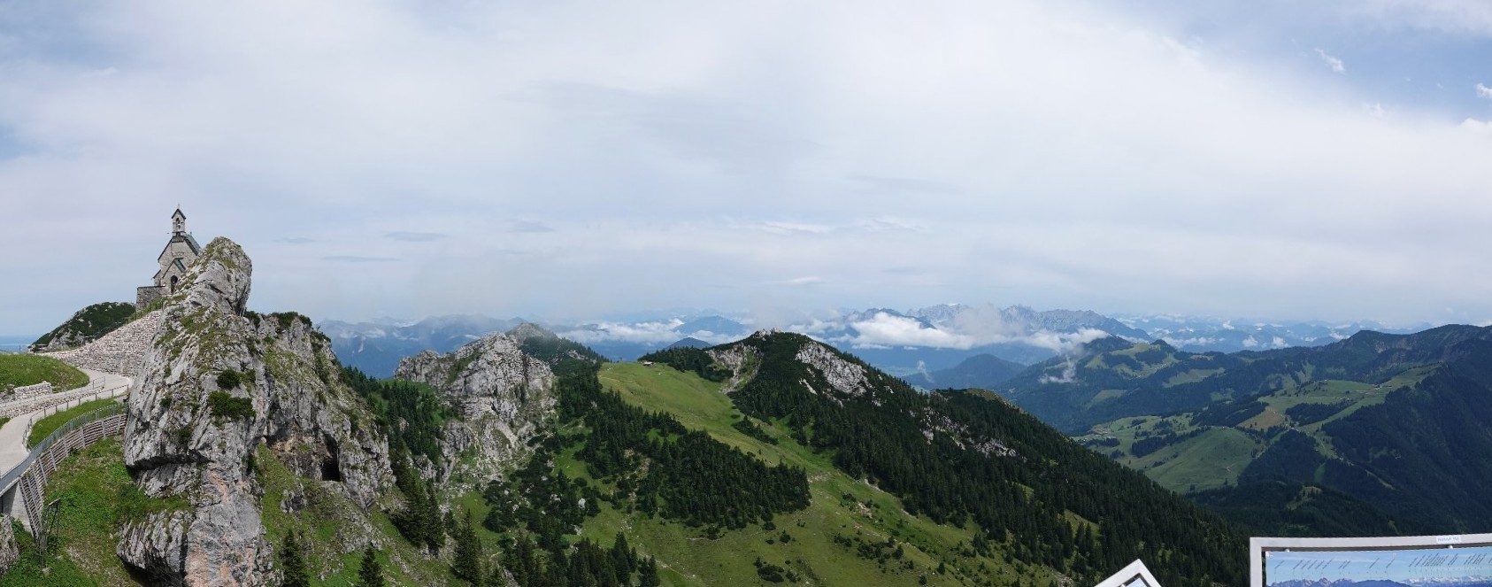 Panorama van een kapel op een rots met de Alpen erachter